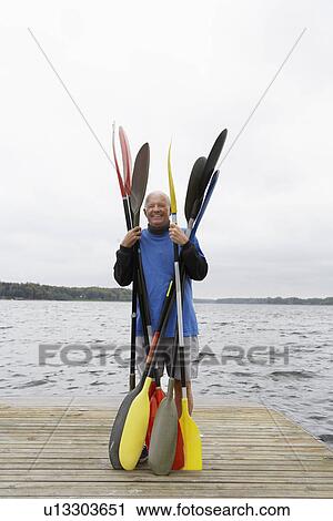 Senior man holding oars on jetty View Large Photo Image Stock Image - Senior man holding oars on jetty. Fotosearch
