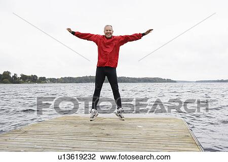 Stock Image - Senior man jumping on jetty. Fotosearch
