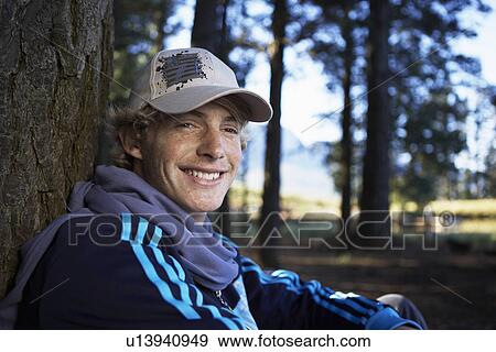 Teenage boy leaning on tree trunk (portrait) View Large Photo Image Stock Photo - Teenage boy leaning on tree trunk (portrait). Fotosearch