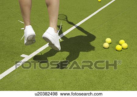 Stock Photo - Tennis player jumping near tennis balls (focus on feet). Fotosearch