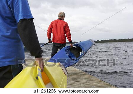 Two senior men carrying kayaks View Large Photo Image Stock Photograph - Two senior men carrying kayaks. Fotosearch