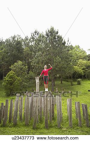 Woman balancing on stump and flexing muscles View Large Photo Image Stock Image - Woman balancing on stump and flexing muscles. Fotosearch