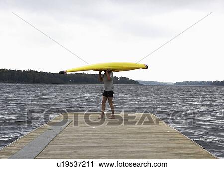 Stock Image - Woman Carrying Kayak on Her Head. Fotosearch