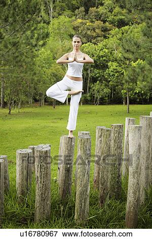 Stock Photo - Woman doing yoga on tree stump. Fotosearch