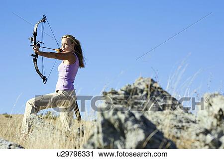 Young woman arrow shooting in field View Large Photo Image Stock Image - Young woman arrow shooting in field. Fotosearch
