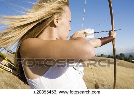 Stock Image - Young woman arrow shooting. Fotosearch