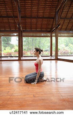 Young woman in sports clothing sitting on wooden floor View Large Photo Image Stock Image - Young woman in sports clothing sitting on wooden floor. Fotosearch