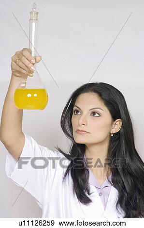 Stock Photo - Close-up of a female technician holding a conical flask. Fotosearch