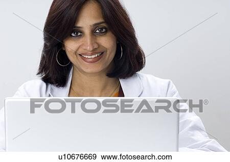 Stock Photo - Portrait of a female doctor in front of a laptop. Fotosearch