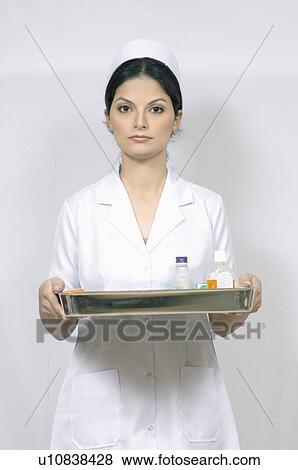Stock Photo - Portrait of a female nurse holding a tray. Fotosearch