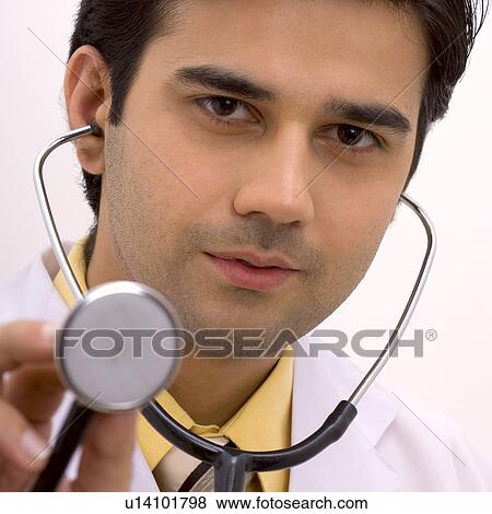Stock Photo - Portrait of a young man holding a stethoscope. Fotosearch