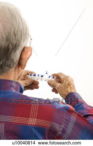 Back over the shoulder view of Caucasion elderly man holding seven-day pill box with Thursday open. View Large Photo Image Picture - Back over the shoulder view of Caucasion elderly man holding seven-day pill box with Thursday open.. Fotosearch