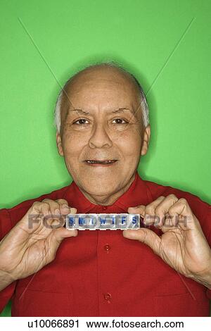Stock Image - Mature adult Caucasian male holding pill organizer.. Fotosearch