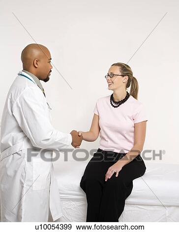 Mid-adult African-American doctor and Caucasion mid-adult female patient shaking hands in doctor's office. View Large Photo Image Stock Photo - Mid-adult African-American doctor and Caucasion mid-adult female patient shaking hands in doctor's office.. Fotosearch
