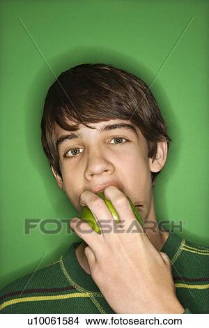 Portrait of Caucasian teen boy biting apple. View Large Photo Image Picture - Portrait of Caucasian teen boy biting apple. . Fotosearch