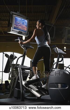 Stock Image - Prime adult Caucasian female on elliptical machine at gym.. Fotosearch