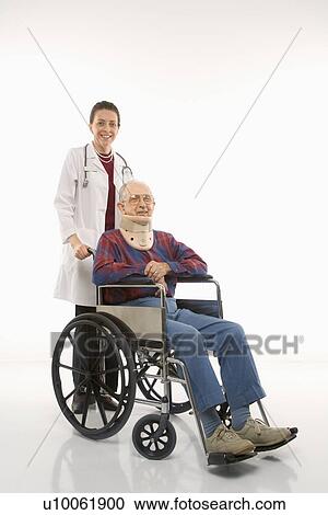 Stock Image - Mid-adult Caucasian female doctor pushing elderly Caucasian male with neck brace in wheelchair.. Fotosearch
