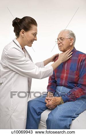 Stock Image - Mid-adult Caucasian female doctor checking an elderly Caucasian male's pulse.. Fotosearch