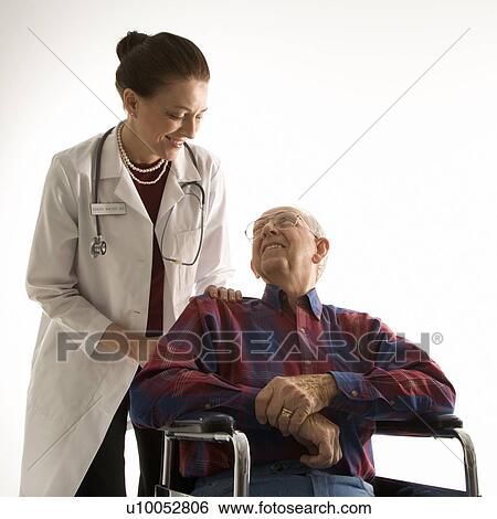 Stock Photograph - Mid-adult Caucasian female doctor looking at an elderly Caucasian male in wheelchair.. Fotosearch