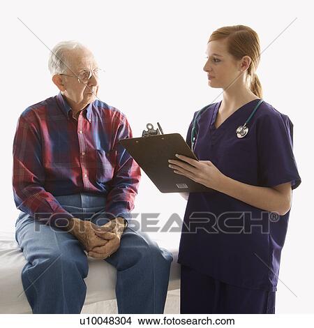Mid-adult Caucasian female in scrubs taking notes from elderly Caucasian male. View Large Photo Image Picture - Mid-adult Caucasian female in scrubs taking notes from elderly Caucasian male.. Fotosearch