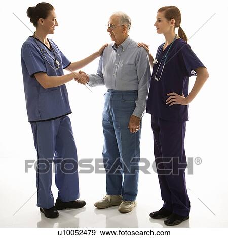 Stock Photo - Mid-adult Caucasian female in scrubs shaking hand of elderly Caucasian male with another mid-adult Caucasian female with hand on his shoulder.. Fotosearch