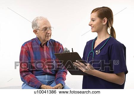 Stock Photograph - Mid-adult Caucasian female in scrubs taking notes from elderly Caucasian male.. Fotosearch