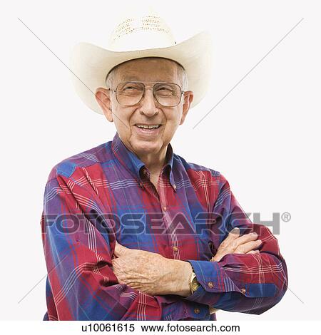 Stock Photography - Portrait of smiling Caucasion elderly man wearing plaid shirt and cowboy hat with arms crossed.. Fotosearch