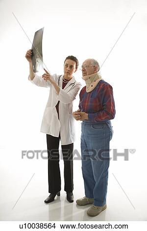 Mid-adult Caucasian female doctor showing x-ray to elderly Caucasian male in neck brace. View Large Photo Image Picture - Mid-adult Caucasian female doctor showing x-ray to elderly Caucasian male in neck brace.. Fotosearch