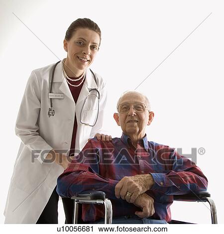 Stock Image - Mid-adult Caucasian female doctor with hands on elderly Caucasian male's shoulder in wheelchair.. Fotosearch