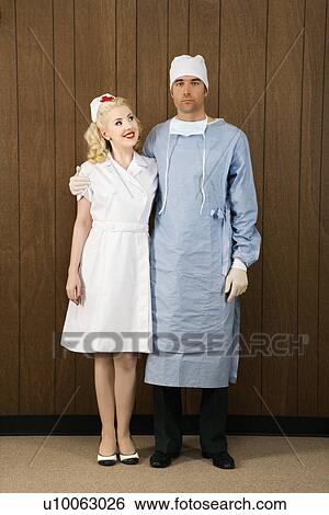 Stock Photograph - Mid-adult Caucasian female nurse and male doctor standing together and smiling.. Fotosearch