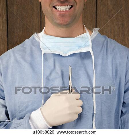 Mid-adult Caucasian male surgeon holding scalpel and smiling. View Large Photo Image Stock Photograph - Mid-adult Caucasian male surgeon holding scalpel and smiling.. Fotosearch