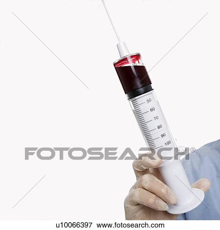 Stock Photo - Mid-adult Caucasian male wearing latex medical gloves and holding a syringe.. Fotosearch