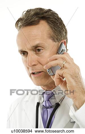 Portrait of a mid-adult Caucasian male doctor with stethoscope around his neck talking on cell phone. View Large Photo Image Picture - Portrait of a mid-adult Caucasian male doctor with stethoscope around his neck talking on cell phone.. Fotosearch