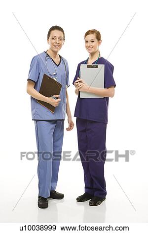 Portrait of Caucasian women doctors in medical scrubs standing holding medical charts against white background. View Large Photo Image Stock Photo - Portrait of Caucasian women doctors in medical scrubs standing holding medical charts against white background.. Fotosearch