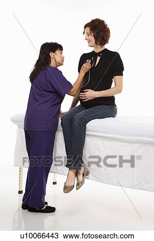Stock Image - Pregnant Caucasian mid-adult woman having vital signs checked by nurse.. Fotosearch