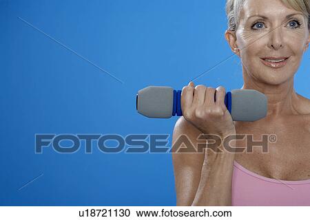 Mature woman exercising with dumbbells View Large Photo Image Stock Image - Mature woman exercising with dumbbells. Fotosearch