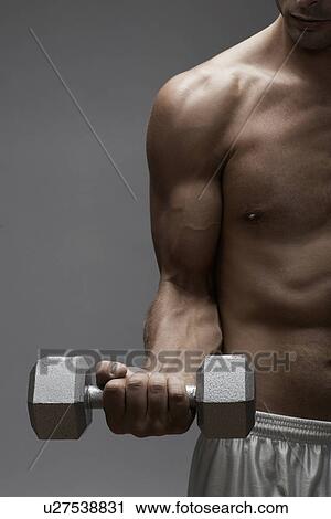 Mid adult man lifting dumbbell (midsection) View Large Photo Image Stock Image - Mid adult man lifting dumbbell (midsection). Fotosearch