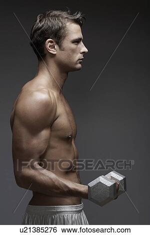 Stock Photograph - Mid adult man lifting dumbbell. Fotosearch