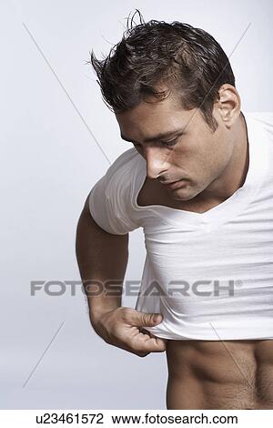 Mid adult man putting T-shirt on View Large Photo Image Stock Image - Mid adult man putting T-shirt on. Fotosearch