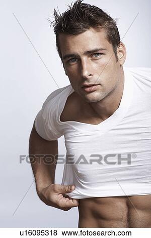 Stock Photo - Mid adult man putting T-shirt on. Fotosearch