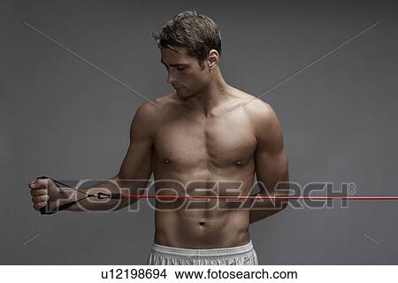 Picture - Mid adult man weight training with cable. Fotosearch
