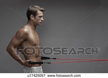 Stock Photo - Mid adult man weight training with cable. Fotosearch