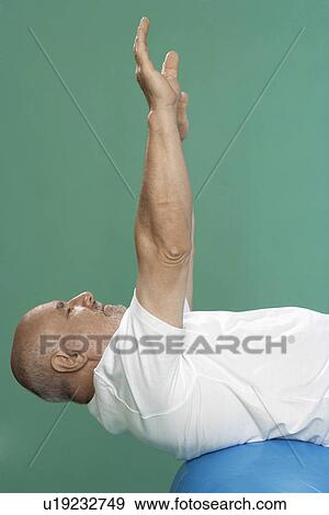 Stock Photo - Senior man exercising on Swiss ball. Fotosearch