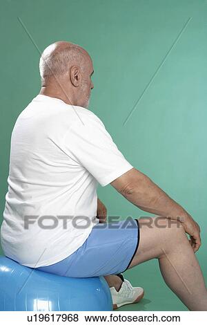 Stock Photo - Senior man exercising on Swiss ball (rear view). Fotosearch