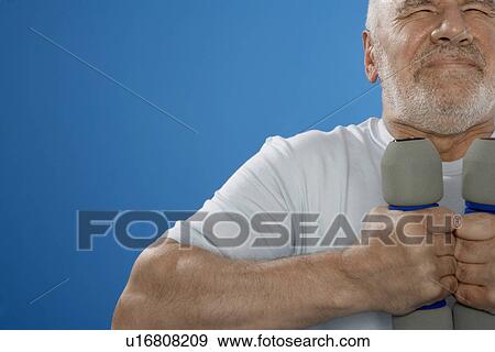 Stock Photo - Senior man training with dumbbells. Fotosearch
