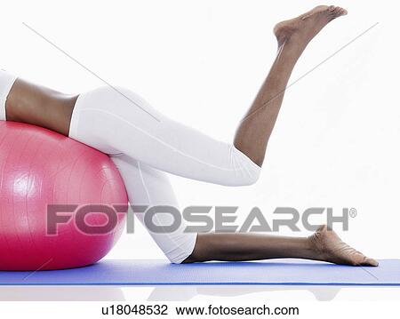Stock Image - Woman doing leg exercises on fitness ball (low section). Fotosearch
