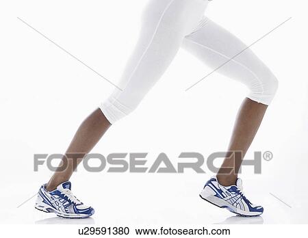 Stock Image - Woman in sports clothing stretching legs (low section). Fotosearch