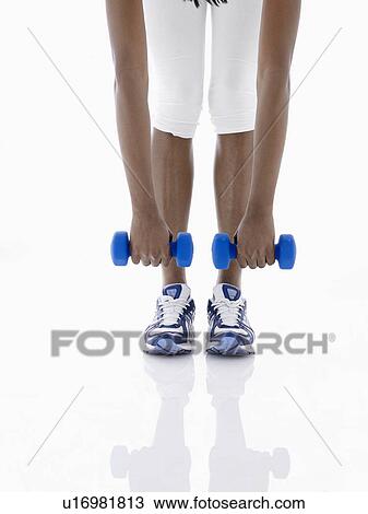 Stock Image - Woman lifting dumbbells (low section). Fotosearch