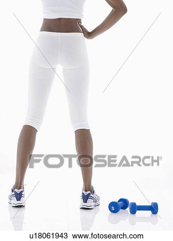 Young woman standing near dumbbells (low section, rear view) View Large Photo Image Stock Image - Young woman standing near dumbbells (low section, rear view). Fotosearch