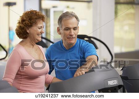 Stock Photo - Man helping woman with treadmill. Fotosearch